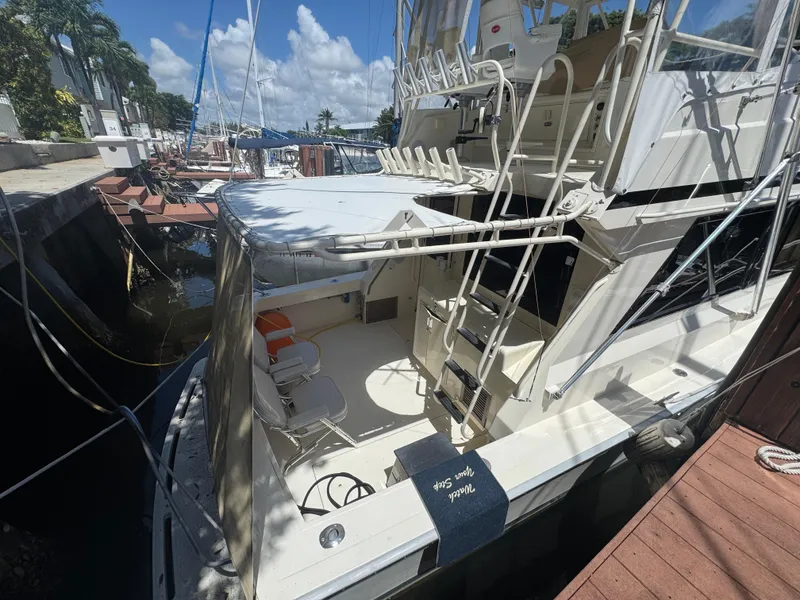 Slide: The Image of 1990 Viking 35 yacht docked, featuring spacious deck and seating under clear blue sky. - 31