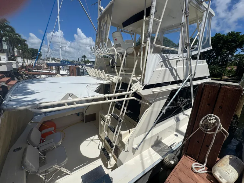 Slide: The Image of 1990 Viking 35 yacht docked, featuring spacious deck and seating area under clear blue sky. - 32