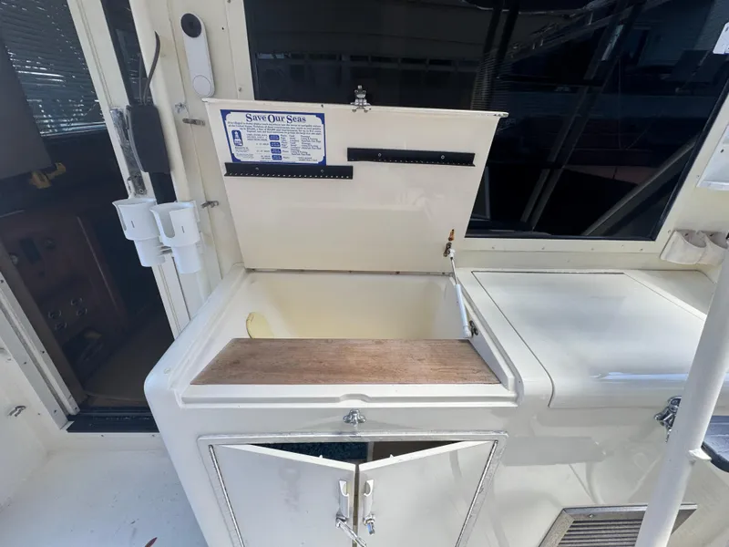 Slide: The Image of Open storage compartment on a 1990 Viking 35 boat, featuring a "Save Our Seas" sign. - 76