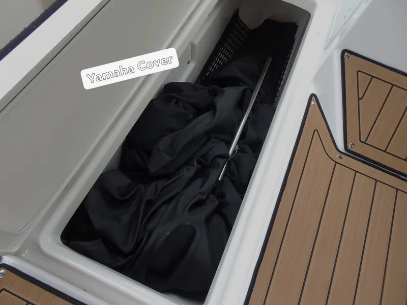 Slide: The Image of 2024 Yamaha Boats 252SE storage compartment with cover and rod. - 21
