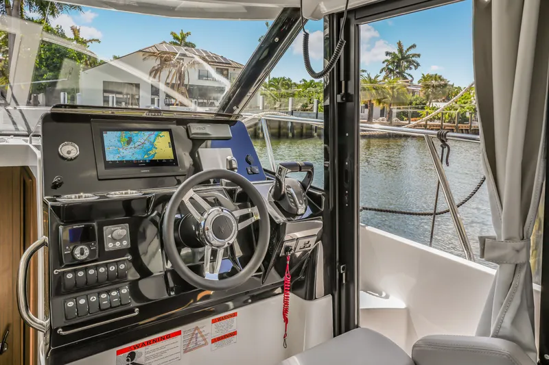 Slide: The Image of 2024 Jeanneau NC1095 Fly helm with navigation system, overlooking a serene waterfront view. - 22