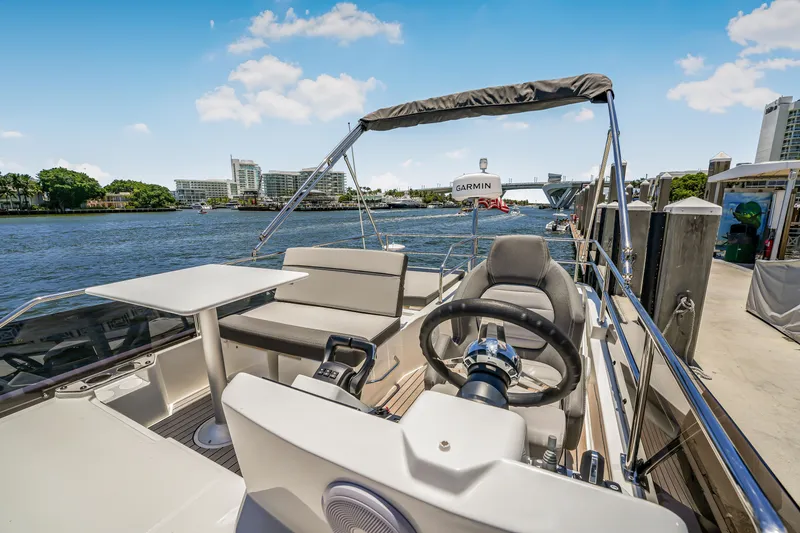 Slide: The Image of 2024 Jeanneau NC1095 Flybridge with helm, seating, and table, docked by waterfront. - 34