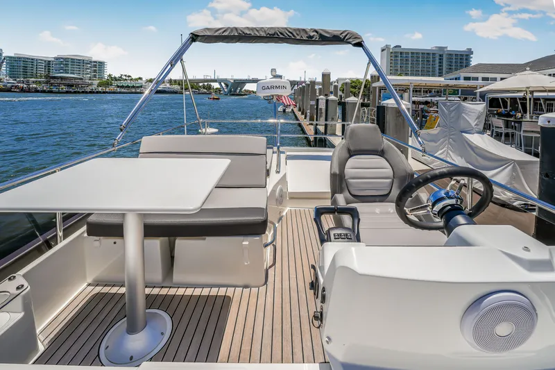 Slide: The Image of 2024 Jeanneau NC1095 Flybridge with helm, seating, and table, docked in a marina. - 35
