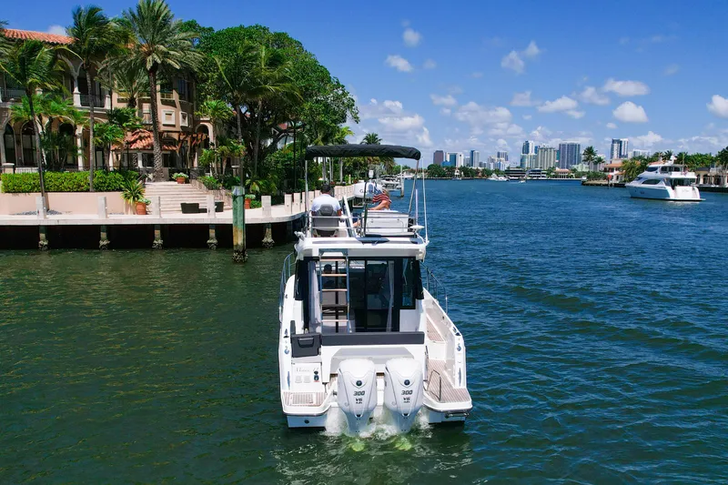 Slide: The Image of 2024 Jeanneau NC1095 Fly cruising in a scenic waterfront setting with city skyline. - 4