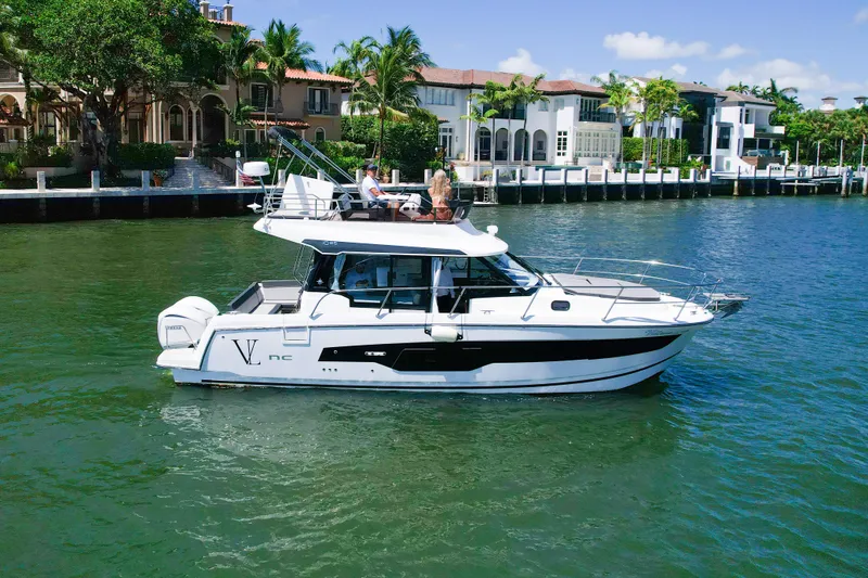 Slide: The Image of 2024 Jeanneau NC1095 Fly yacht cruising near luxury waterfront homes. - 5