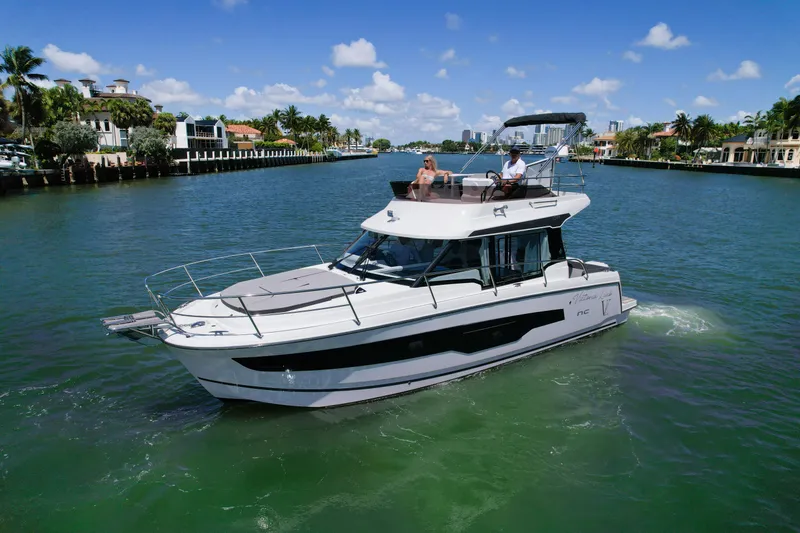 Slide: The Image of 2024 Jeanneau NC1095 Fly cruising on a scenic waterway under a clear blue sky. - 6