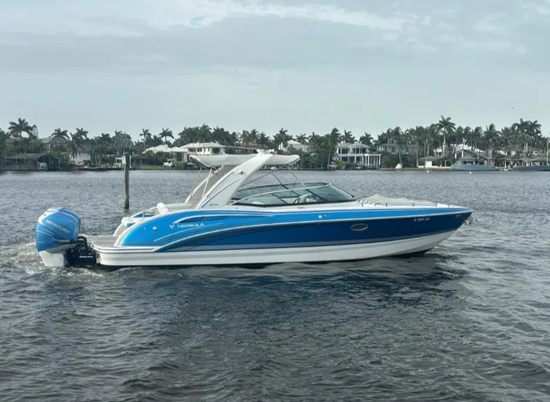 Slide: The Image of 2020 Formula 310 Bowrider boat on water, blue and white design, palm trees in background. - 2