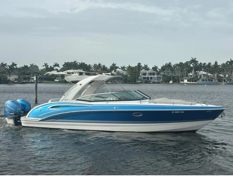 Slide: The Image of 2020 Formula 310 Bowrider boat on water, blue and white design, coastal background. - 3