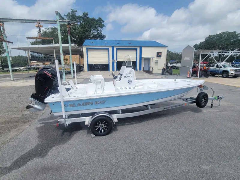 Slide: The Image of 2025 Blazer Bay boat on trailer, parked outdoors near a blue-roofed building. - 4