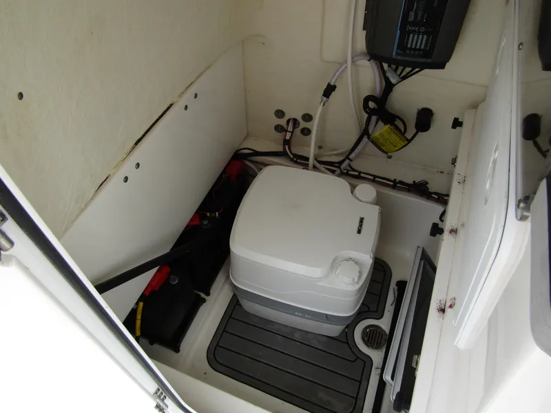 Slide: The Image of 2021 Tidewater 2700 Carolina Bay boat interior with portable toilet and storage area. - 21