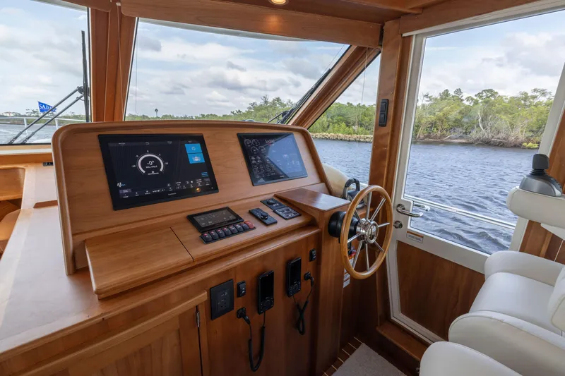 Slide: The Image of 2026 Sabre 58 Salon Express helm with modern controls and scenic river view. - 13