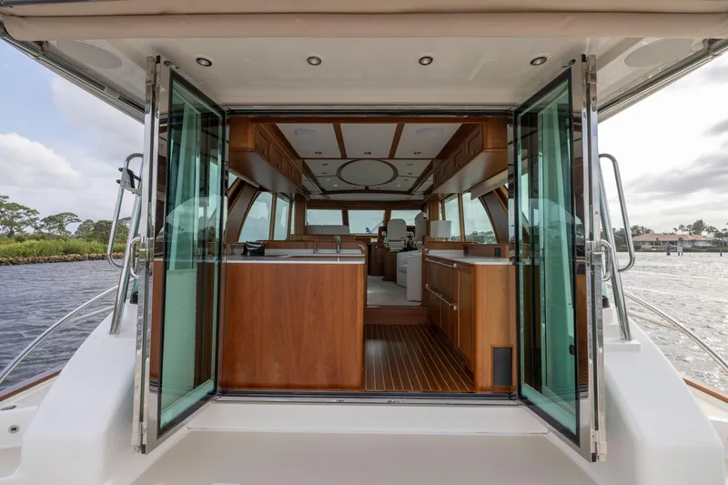 Slide: The Image of 2026 Sabre 58 Salon Express yacht interior with open glass doors, showcasing luxurious wood finishes. - 2