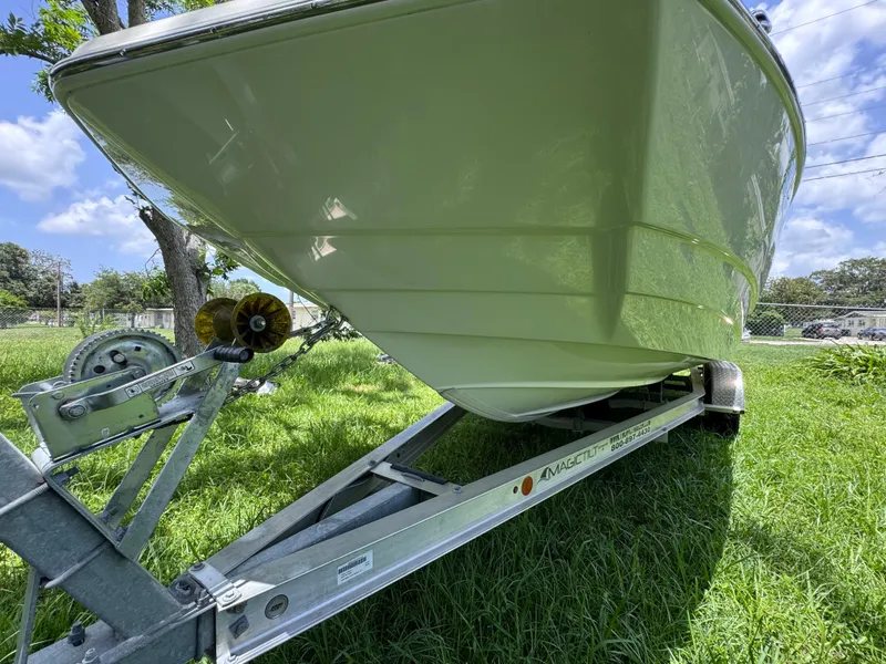 Slide: The Image of 2018 NauticStar DC 243 Sport Deck boat on trailer, parked on grass. - 10