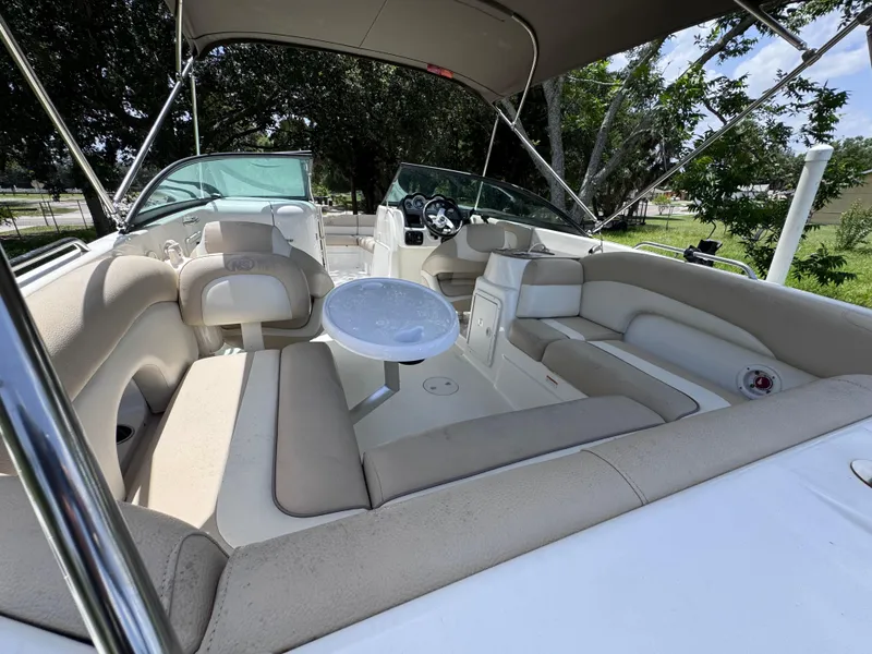 Slide: The Image of 2018 NauticStar DC 243 Sport Deck boat interior with beige seating and table. - 25