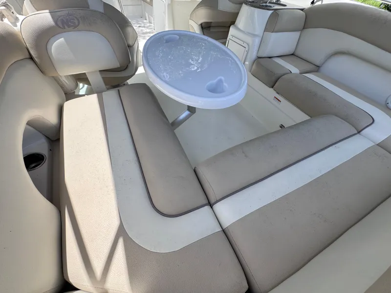 Slide: The Image of 2018 NauticStar DC 243 Sport Deck interior with beige seating and a small round table. - 27