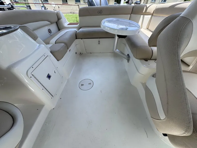 Slide: The Image of 2018 NauticStar DC 243 Sport Deck interior with beige seating and a small table. - 29