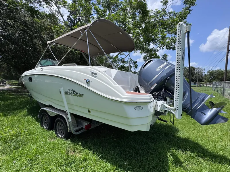 Slide: The Image of 2018 NauticStar DC 243 Sport Deck boat on trailer, parked on grass. - 3