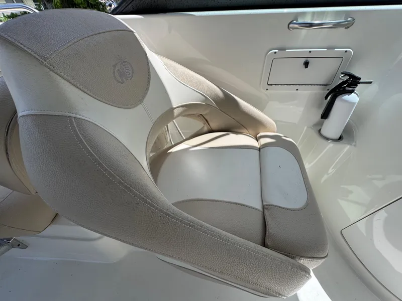 Slide: The Image of 2018 NauticStar DC 243 Sport Deck seat with beige upholstery and safety equipment. - 34
