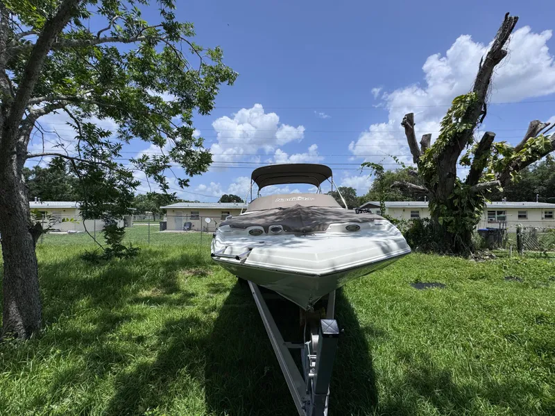 Slide: The Image of 2018 NauticStar DC 243 Sport Deck boat on trailer, parked on grass under blue sky. - 49