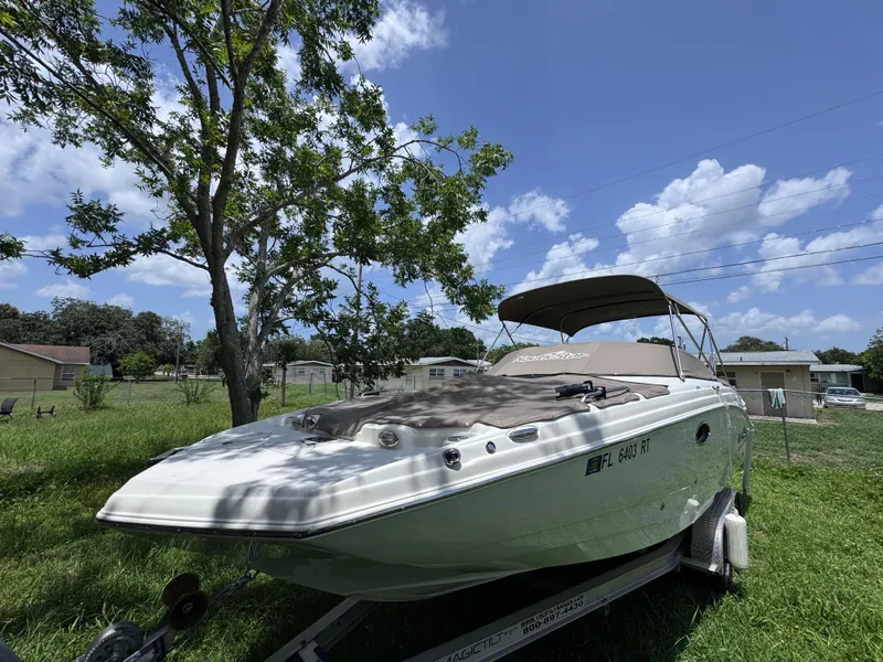 Slide: The Image of 2018 NauticStar DC 243 Sport Deck boat on trailer, parked in grassy yard under blue sky. - 52