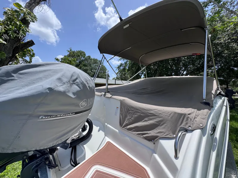 Slide: The Image of 2018 NauticStar DC 243 Sport Deck boat with Yamaha engine, covered and docked outdoors. - 56