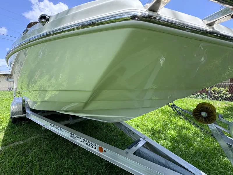 Slide: The Image of 2018 NauticStar DC 243 Sport Deck boat on trailer, parked on grass. - 9