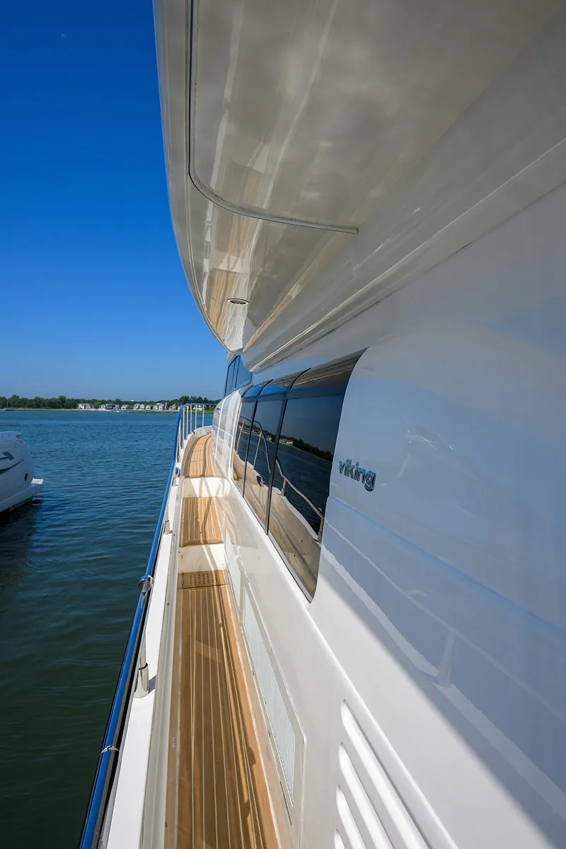 Slide: The Image of 2006 Viking Princess Sport Cruisers yacht on calm water, showcasing sleek design and wooden deck. - 11