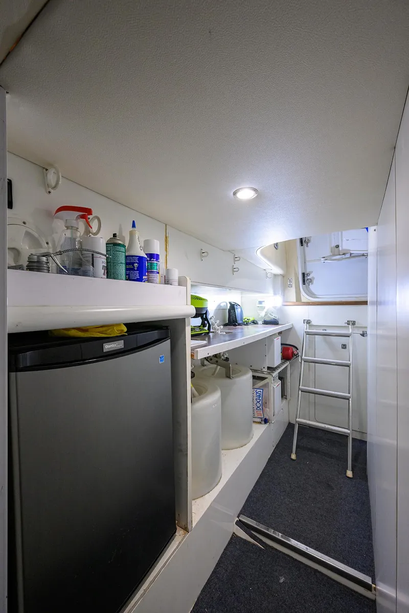 Slide: The Image of 2006 Viking Princess Sport Cruisers interior with mini fridge, storage shelves, and ladder. - 49