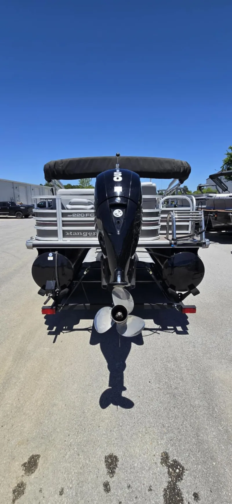 Slide: The Image of 2020 Ranger Reata 220FC boat, rear view with outboard motor, parked on pavement. - 10