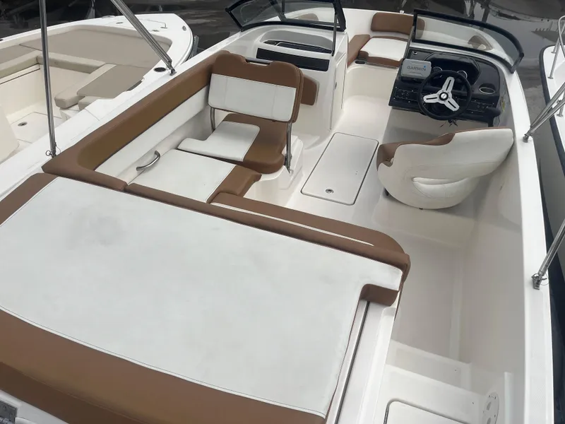 Slide: The Image of 2021 Bayliner VR5 Bowrider OB interior with white and brown seating, steering wheel, and spacious layout. - 9
