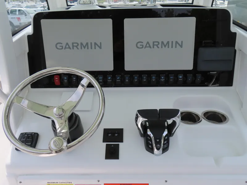 Slide: The Image of Control panel of 2025 Sea Hunt Gamefish 25 with Garmin displays and steering wheel. - 25