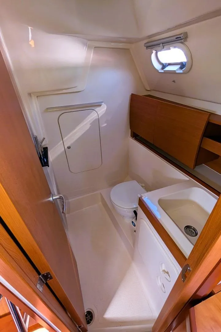 Slide: The Image of Compact bathroom in a 2014 Hanse 325 yacht, featuring a toilet, sink, and wooden cabinetry. - 17