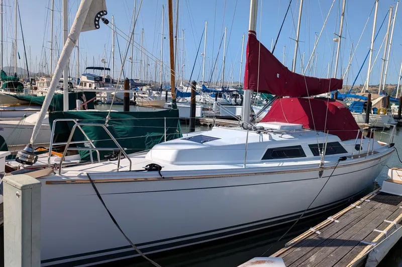 Slide: The Image of 2014 Hanse 325 sailboat docked in marina, featuring red sail cover and sleek white hull. - 2