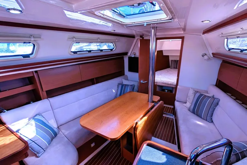Slide: The Image of 2014 Hanse 325 yacht interior with cozy seating, wooden table, and striped cushions. - 21