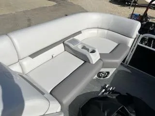 Slide: The Image of 2023 Sweetwater 2286SBX boat seating with cup holders, featuring white and gray upholstery. - 8