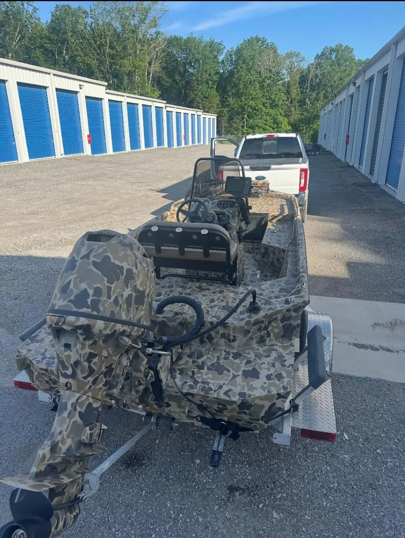 Slide: The Image of 2025 Excel 1860 F4 Shallow Water Pro Console boat on trailer, parked near storage units. - 10