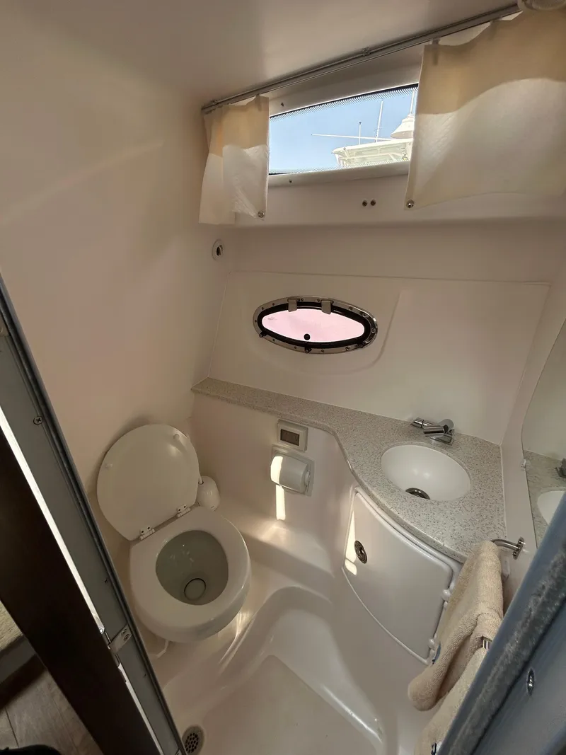 Slide: The Image of 2017 Regal 30 Express boat bathroom with toilet, sink, and window. - 10