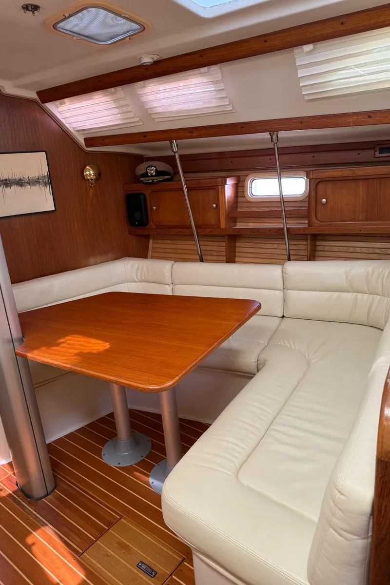 Slide: The Image of Interior of 1998 Catalina 400 sailboat with wooden table and white leather seating. - 21
