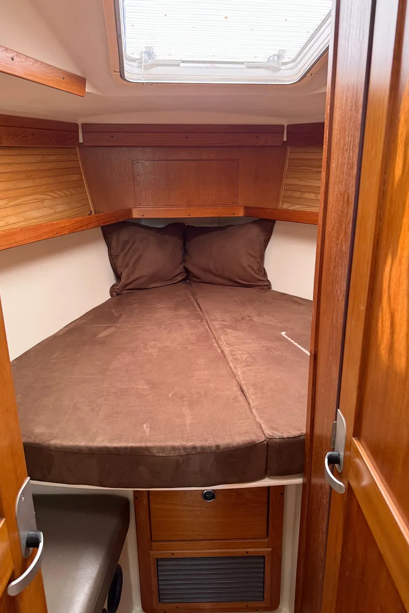 Slide: The Image of 1998 Catalina 400 sailboat cabin with cozy brown bedding and wooden interior. - 37