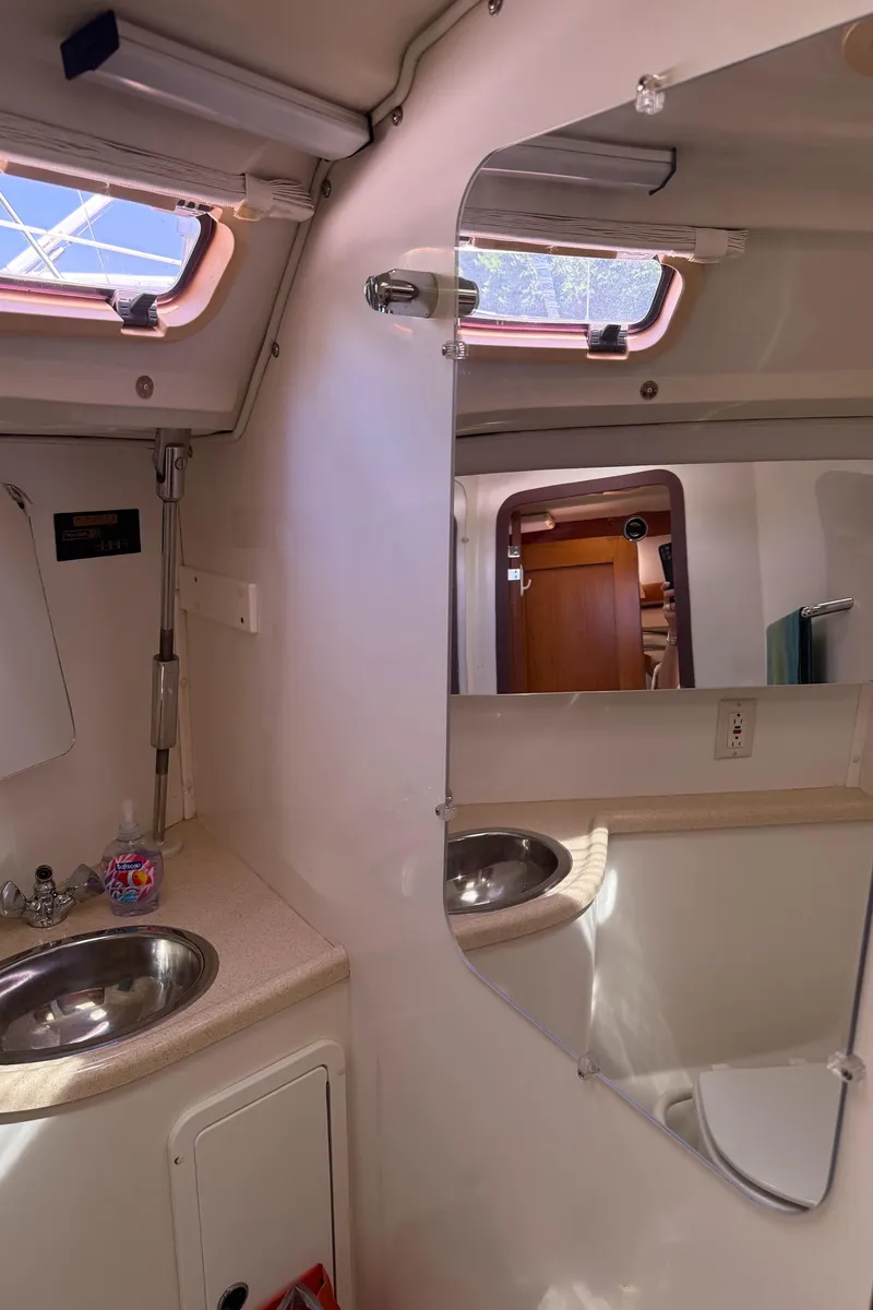 Slide: The Image of Interior of 1998 Catalina 400 yacht bathroom with sink, mirror, and porthole windows. - 40