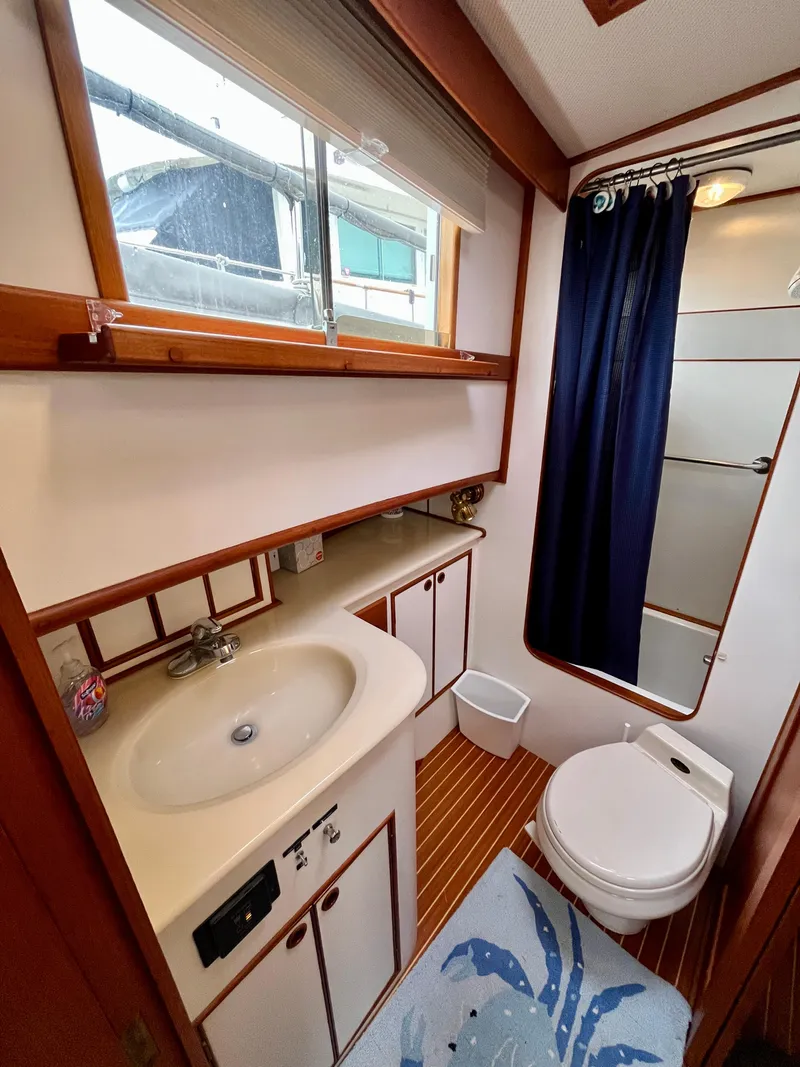 Slide: The Image of Bathroom interior of a 1997 Grand Banks 49 Classic yacht, featuring a sink, toilet, and shower. - 32