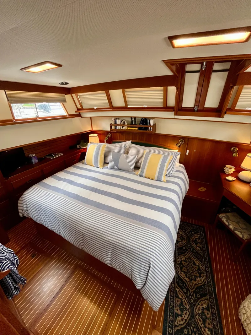 Slide: The Image of Luxurious 1997 Grand Banks 49 Classic yacht bedroom with striped bedding and elegant wood finishes. - 34