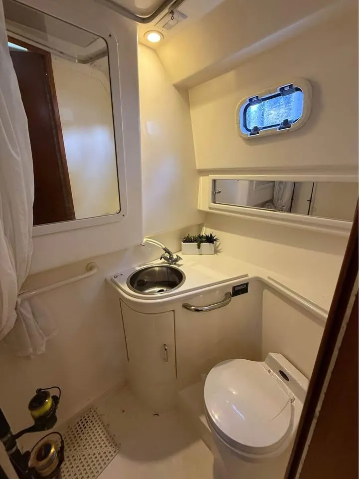 Slide: The Image of 2001 Cabo 35 Express boat bathroom with sink, toilet, and porthole window. - 15