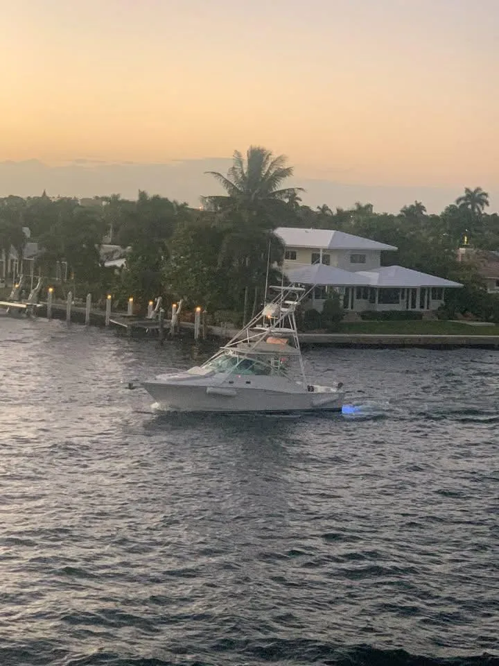 Slide: The Image of 2001 Cabo 35 Express boat cruising near waterfront homes at sunset. - 17