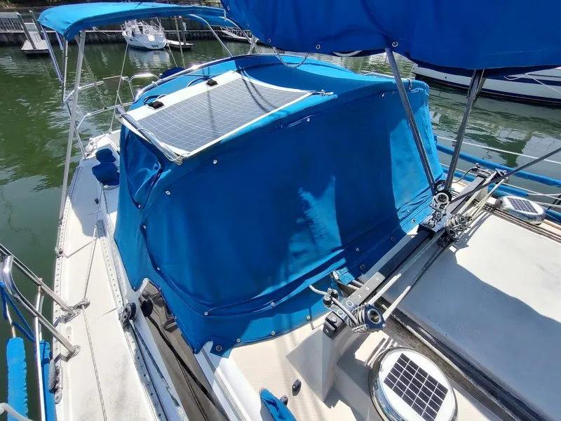 Slide: The Image of 1987 Catalina C-34 sailboat with blue canopy and solar panels docked at marina. - 10