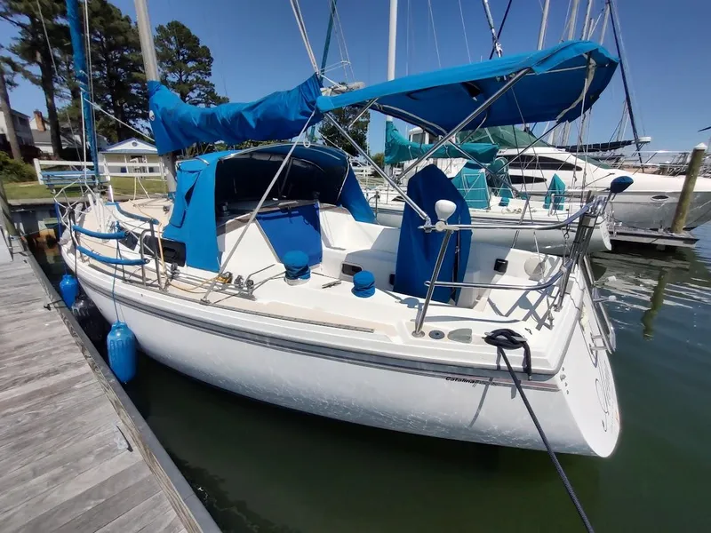 Slide: The Image of 1987 Catalina C-34 sailboat docked, featuring blue covers and a spacious deck. - 3