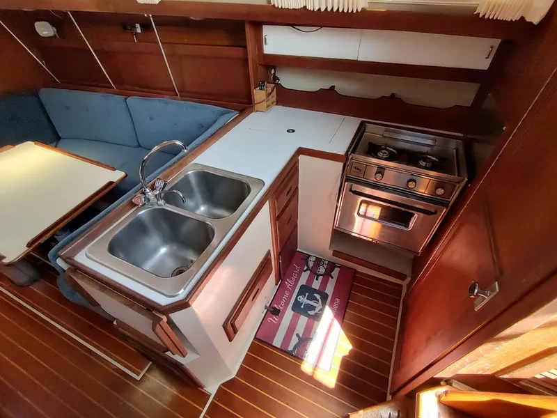 Slide: The Image of 1987 Catalina C-34 yacht interior with kitchen, double sink, stove, and seating area. - 35