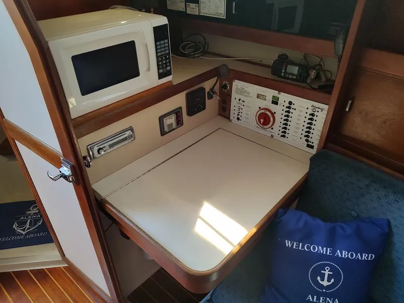 Slide: The Image of 1987 Catalina C-34 yacht interior with microwave, control panel, and welcome pillow. - 42
