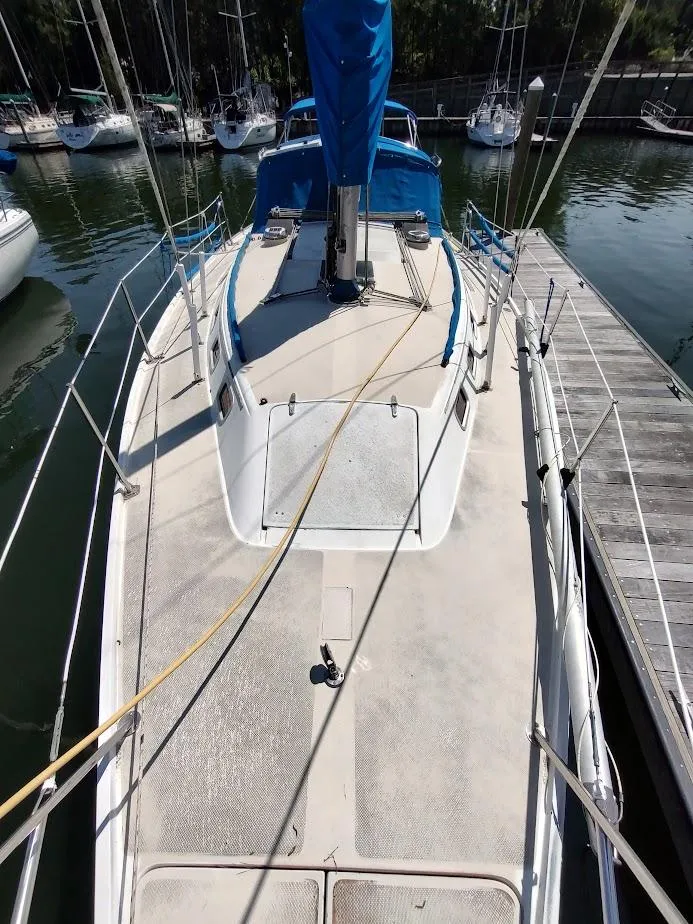 Slide: The Image of 1987 Catalina C-34 sailboat docked, featuring a clean deck and blue sail cover. - 8