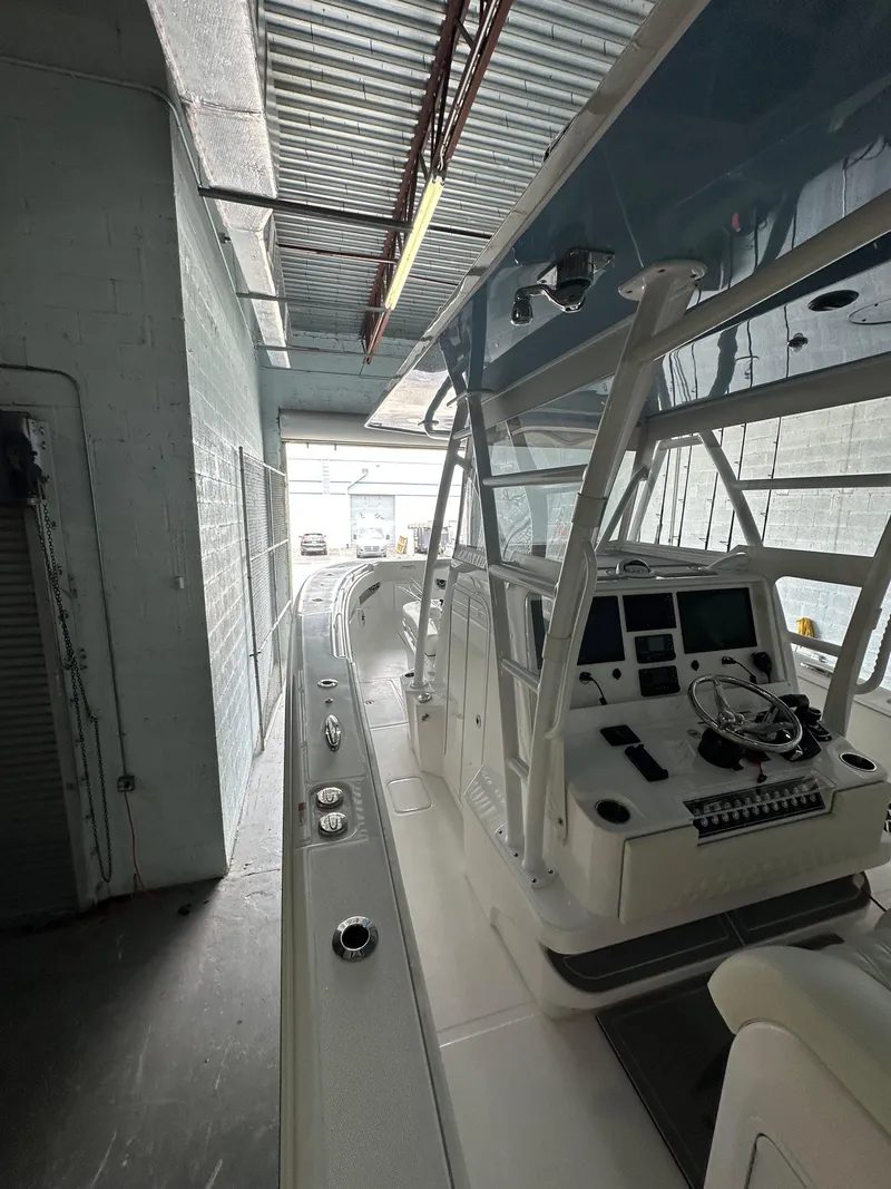 Slide: The Image of 2025 Invincible 36 Open boat in a garage, showcasing helm and controls. - 10